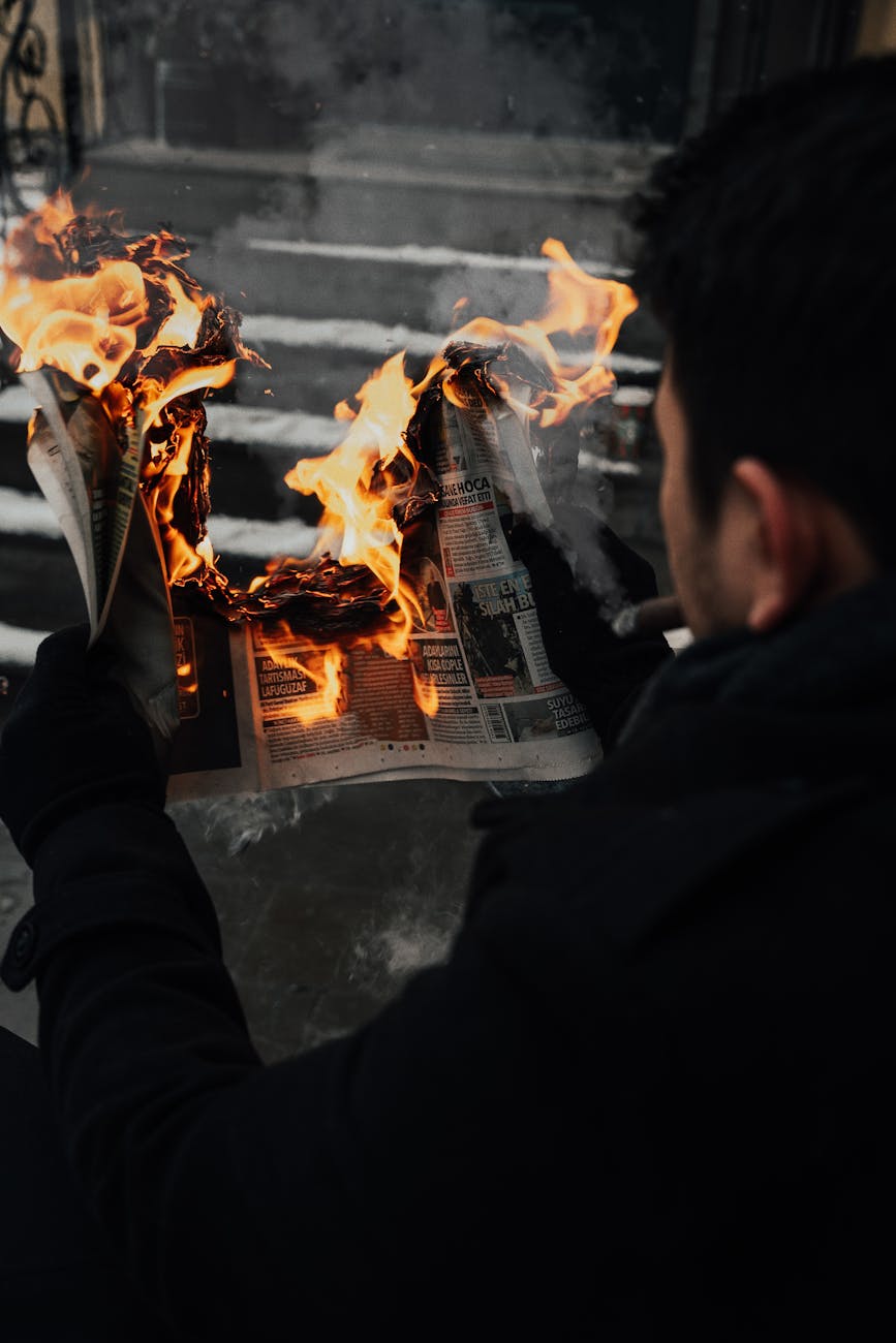 a man holding a burning newspaper