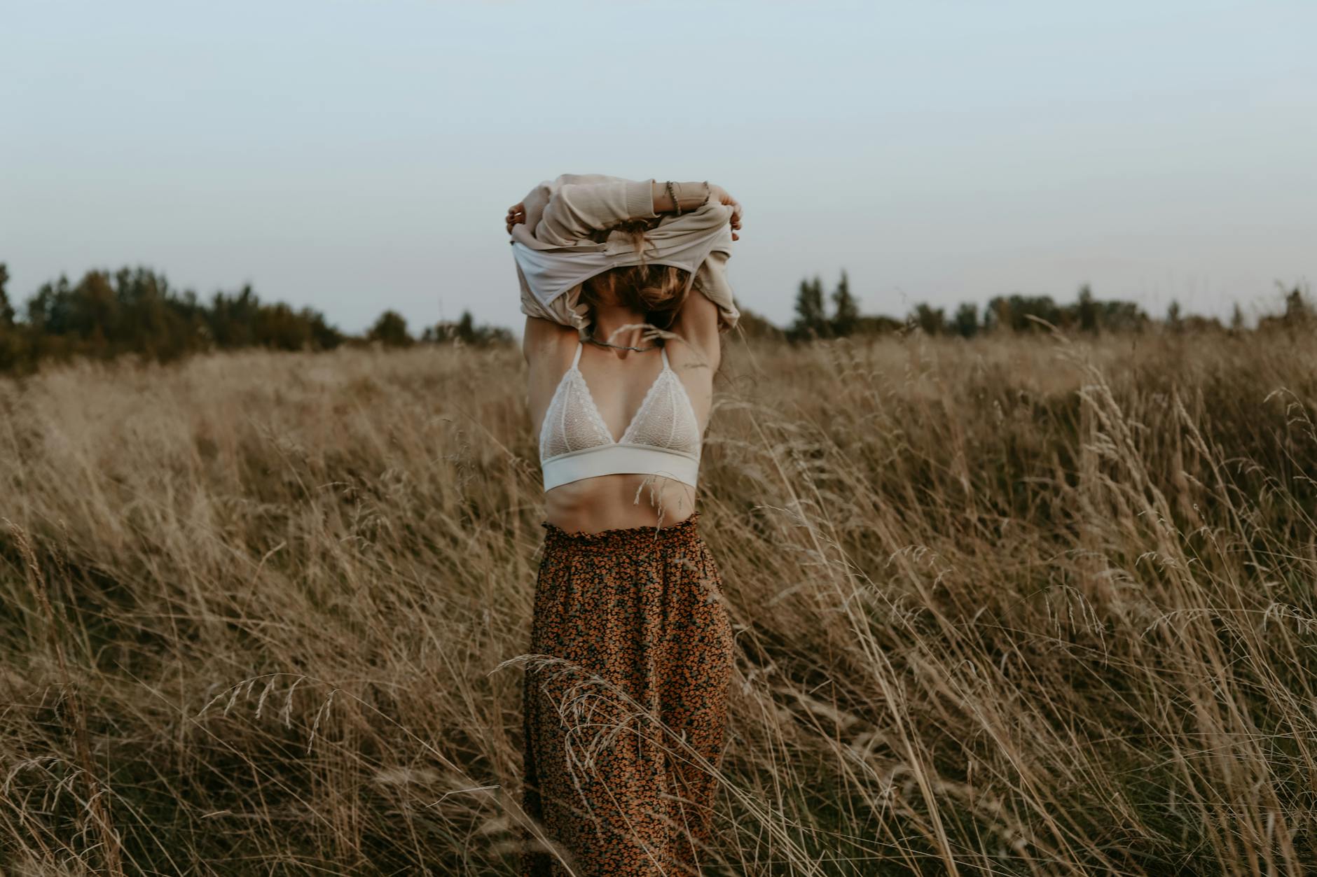 Woman in field removing clothing